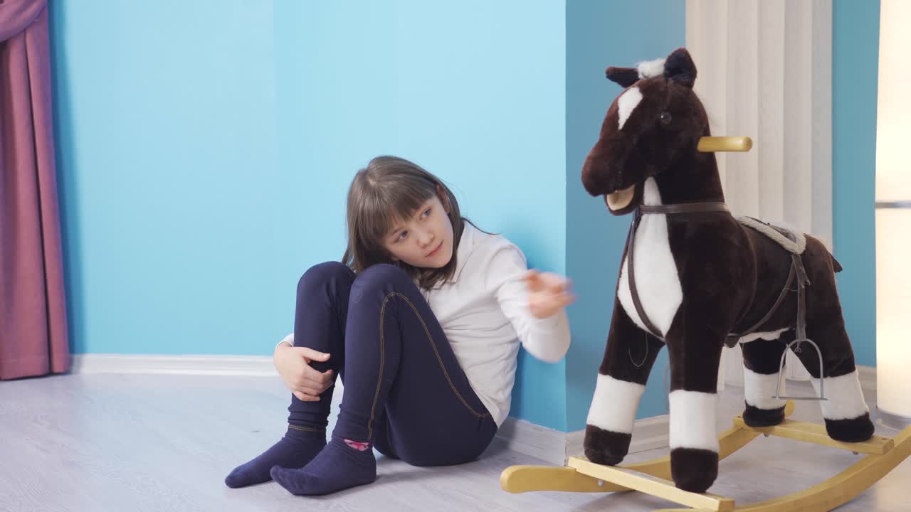 지루한 작은 소녀는 집의 방에서 불행합니다.