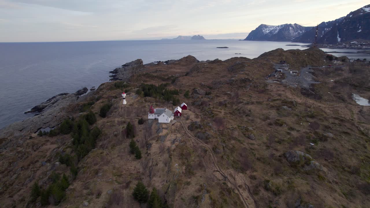 Aerial orbit drone shot of a old Norwegian historical lighthouse in Lofoten with the famous village Sorvagen in the background