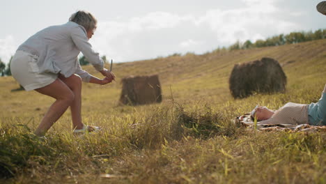 tourist in net cloth and sunglasses lying on mat with warm smile observing hand while dog on leash stays close, peaceful countryside setting, golden sunlight