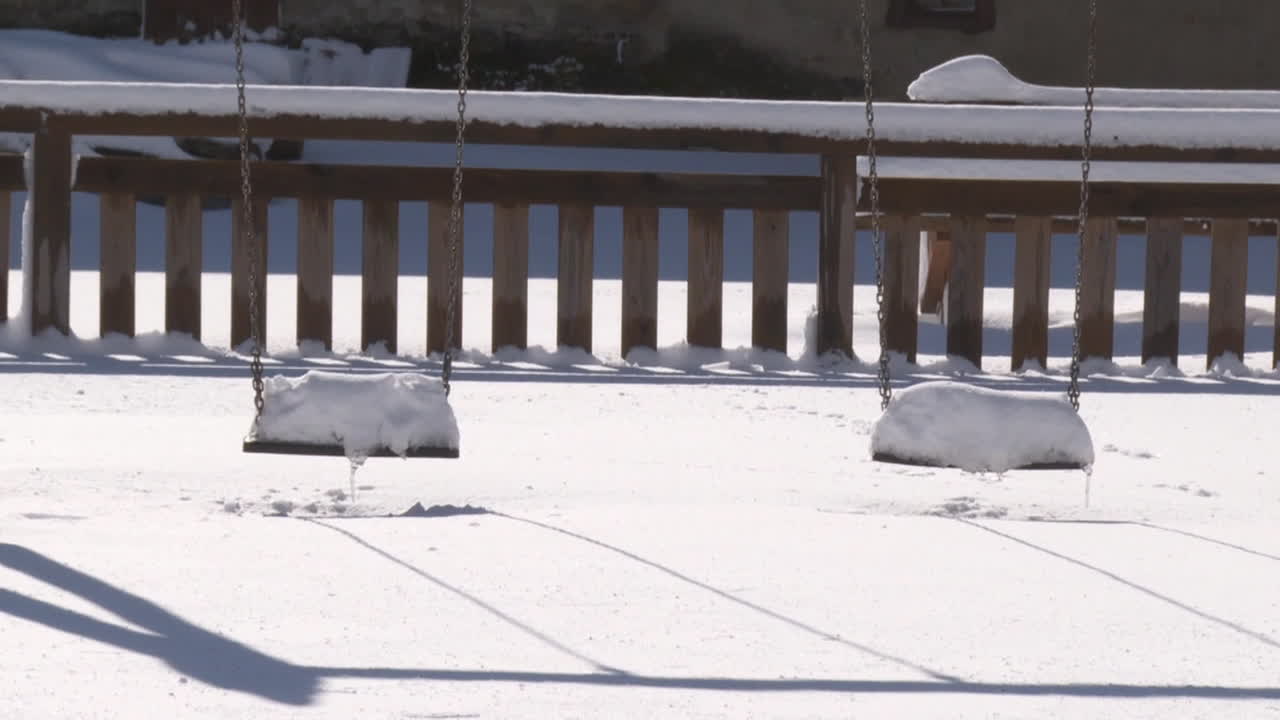 Empty playground swings covered in snow