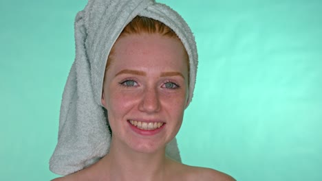 mujer pelirroja con pecas de pie con una toalla en la cabeza