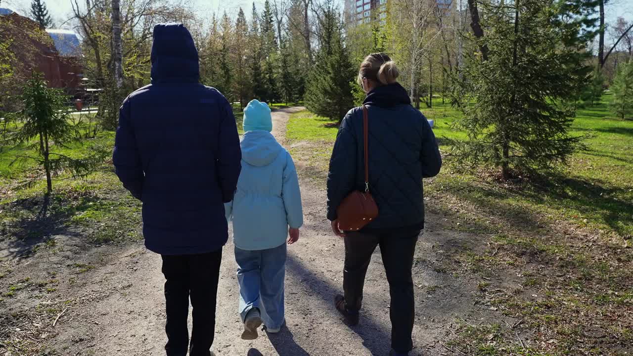 Tre personer går på en sti i en grøn park