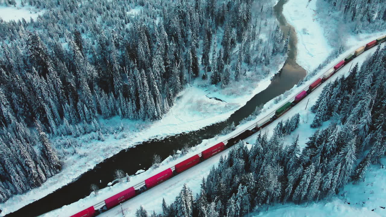 Train Moving On The Track On Snowy Mountain Near Creek At Glacier National Park Of Canada, BC. aerial drone