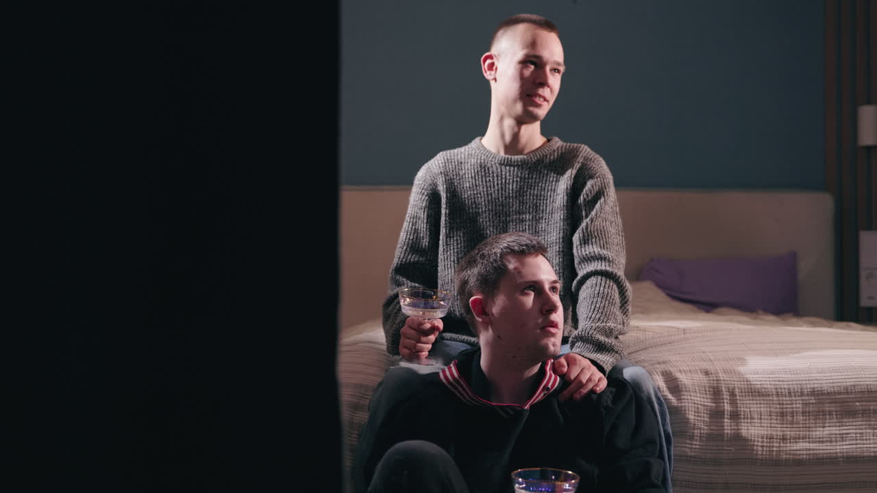 dos hombres viendo algo juntos, disfrutando de bebidas