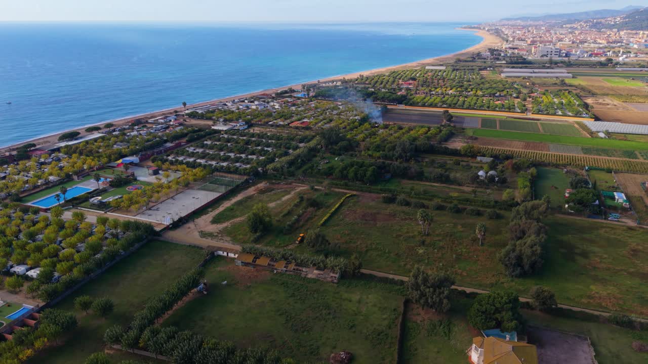 Picturesque aerial view showcasing the confluence of the tordera river and the mediterranean sea, with lush green farmland, campsites, and the town of malgrat de mar along the coast