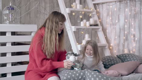 caring-mom-and-cute-blond-daughter-play-with-soft-toy-deer