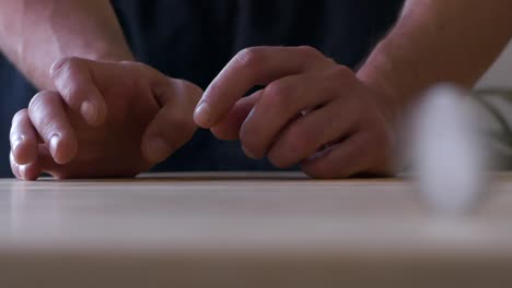 skilled man hands holding coin and hitting it to spin and bounce along wooden table, slow motion close up shot