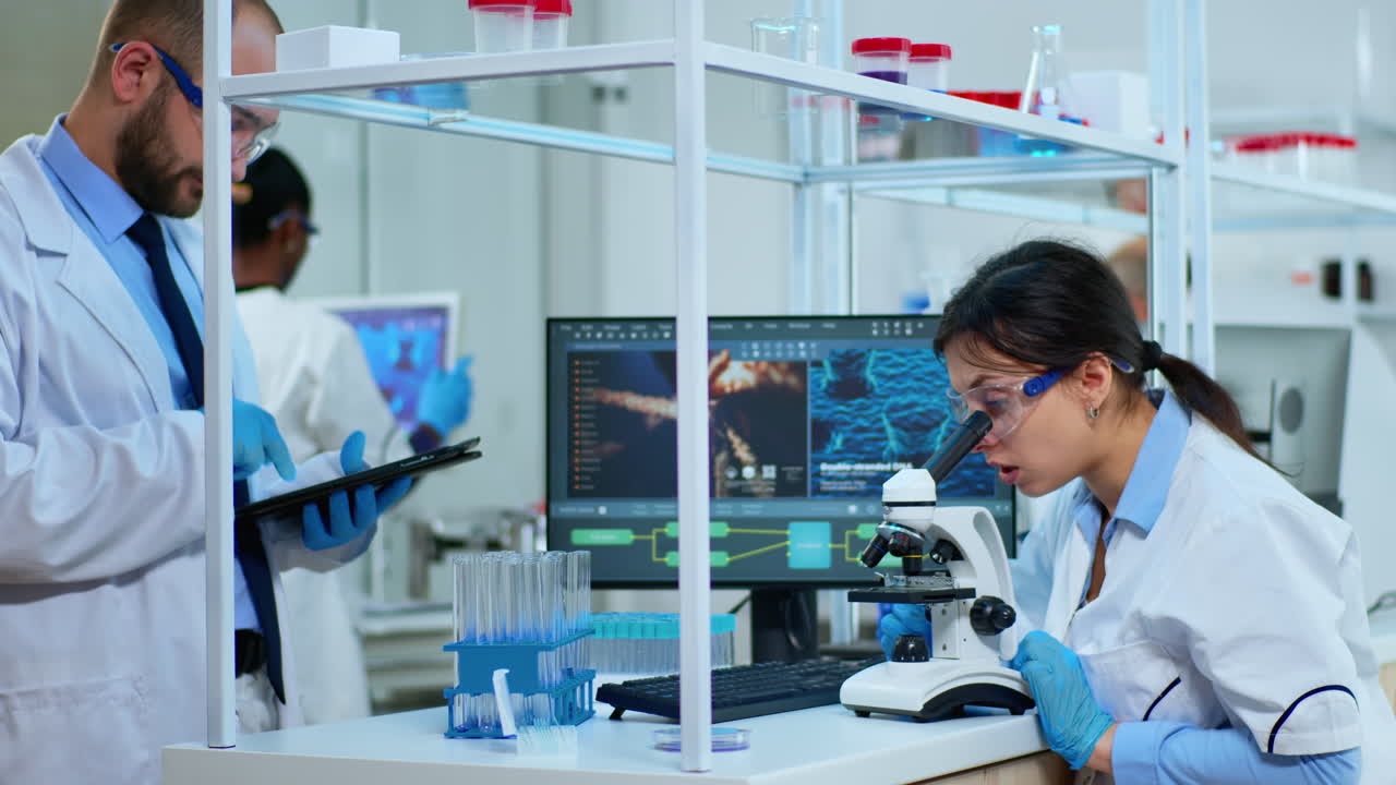 Scientist team analysing results using microscope