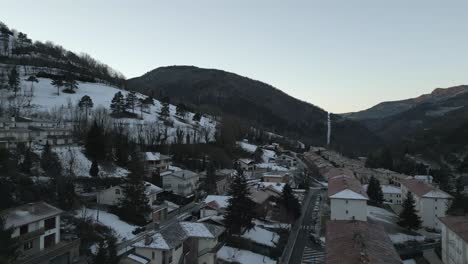 aerial drone fly above houses and snowy hills landscape, winter in the pyrenees, ribes de freser, girona, catalonia