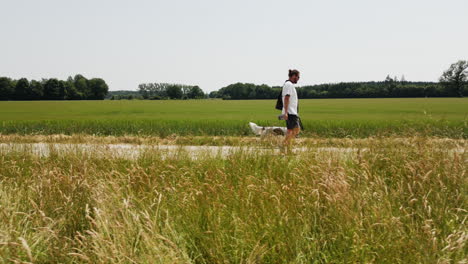 Drohnenaufnahme-Eines-Mannes,-Der-Mit-Einem-Hund-Auf-Dem-Deutschen-Land-Spazieren-Geht