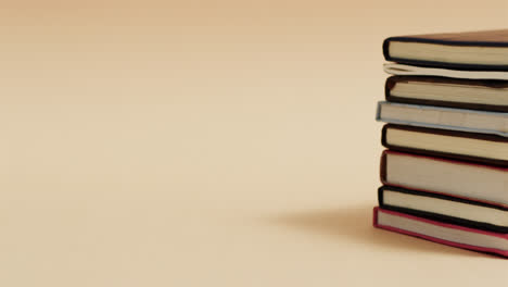primer plano de una pila de libros con espacio de copia en un fondo beige, en cámara lenta