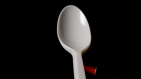 flame melts handle of a plastic spoon in front of black background