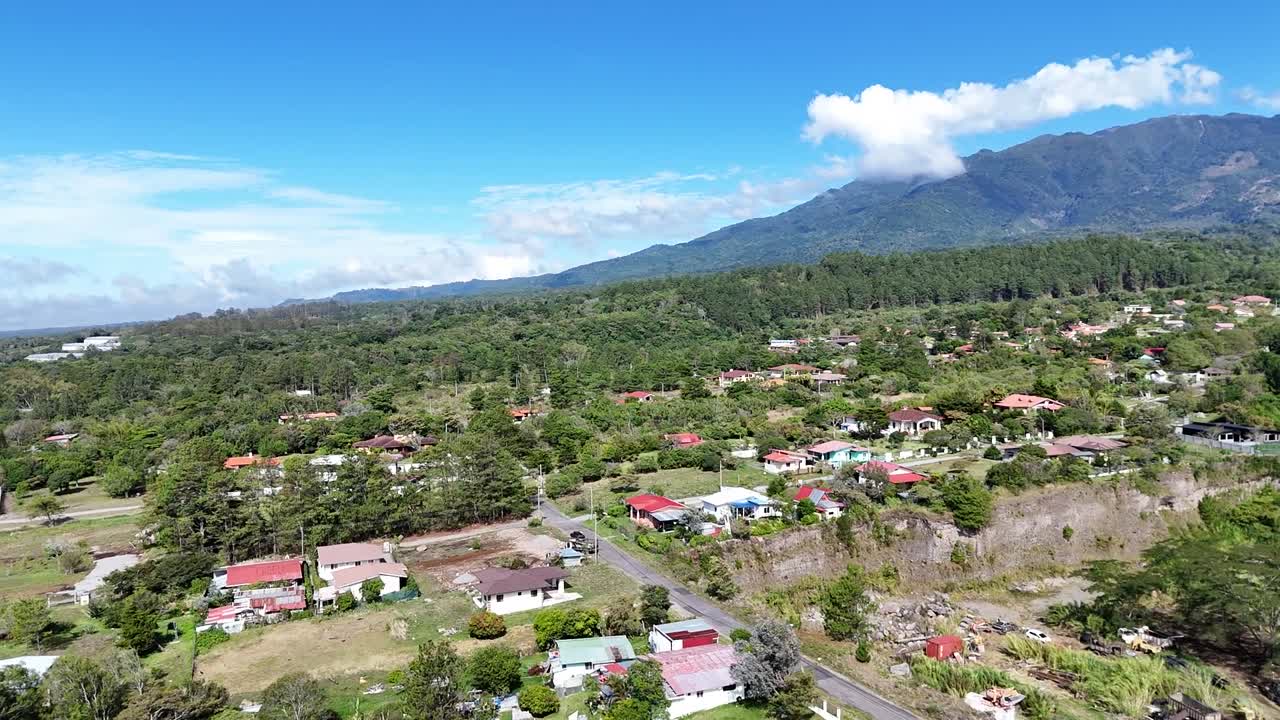 Vídeo aéreo de drone de uma pequena cidade cercada por árvores e montanhas.