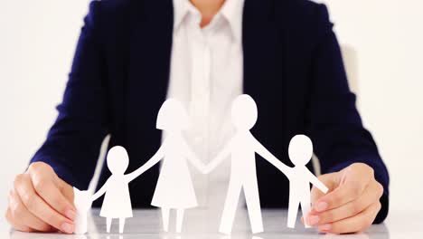 businesswoman holding paper cut out of a family