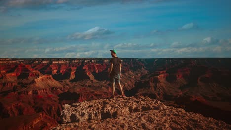 Cinemagraph---seamless-video-loop-time-lapse-of-a-young-man-looking-over-the-deep-void-and-rock-formations-at-famous-Grand-Canyon-in-Arizona,-America---USA-with-clouds-passing-across-the-blue-sky