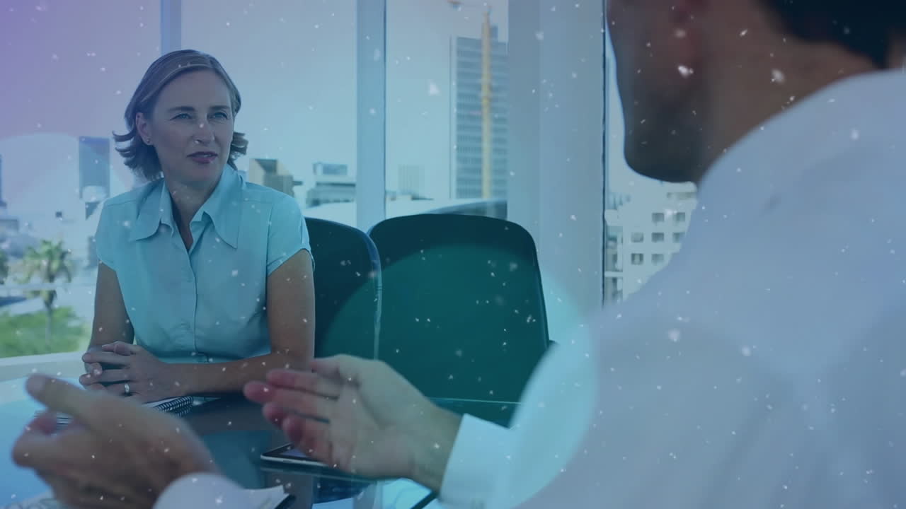 Partículas blancas flotando con una empresaria y un empresario caucásicos discutiendo en la oficina.