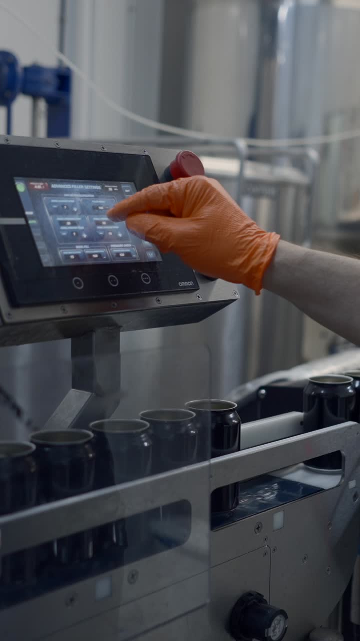 Worker adjusting settings on a beverage canning machine