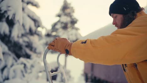 man is holding a snow sleigh shovel covered with fresh ice snow