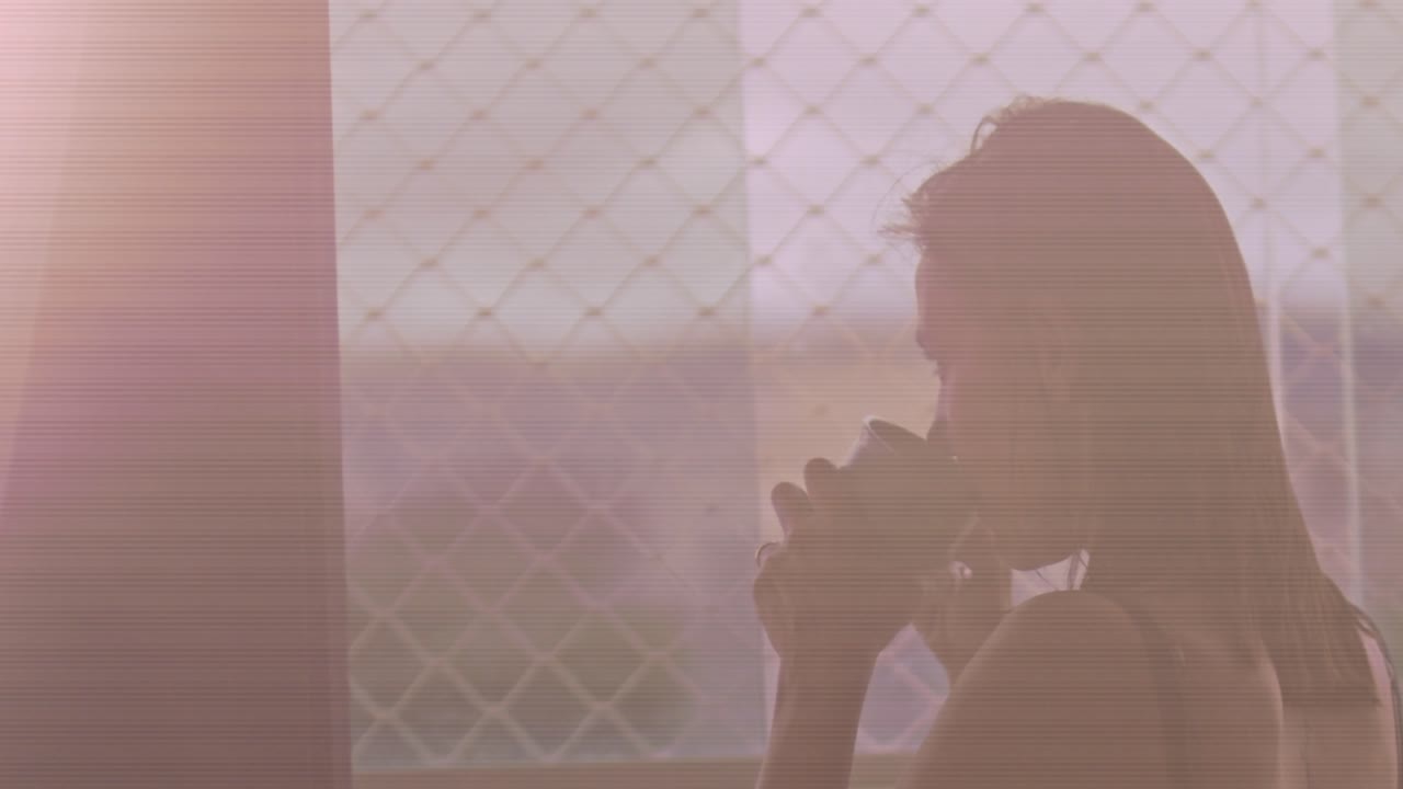 창 밖을 내다보며 아침에 커피를 마시는 중년의 브루네트 여성