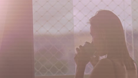 Middle-aged-brunette-woman-drinking-coffee-in-the-morning,-looking-out-window