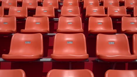 muchos asientos naranjas están en el estadio. el camión disparó de derecha a izquierda.