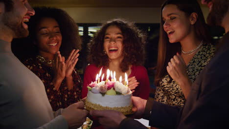 people singing happy birthday to excited woman. friends present cake on party.