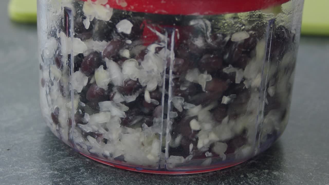 퓌레를 만들기 위해 수동 주방 기계로 강낭콩과 양파를 자르는 중