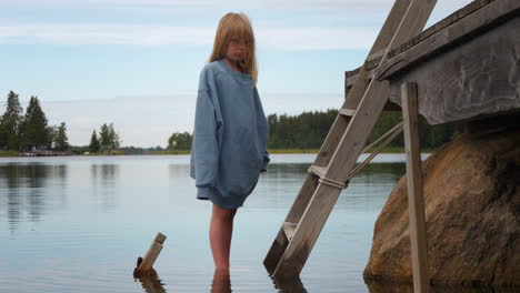 portrait of sad blonde girl standing in water worried about rising sea levels