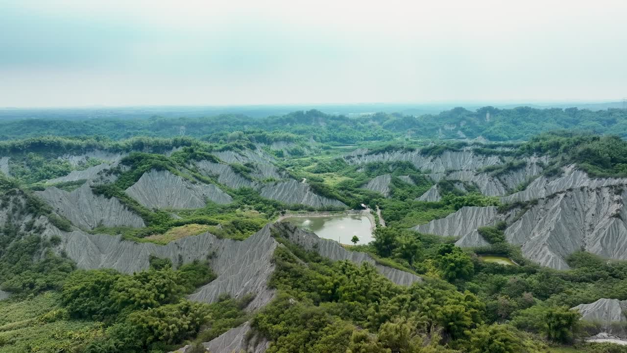 vuelo aéreo sobre área volcánica de barro con lago y paisaje en un día nublado en taiwán