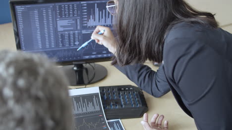 serious financial broker and investor sitting at monitor