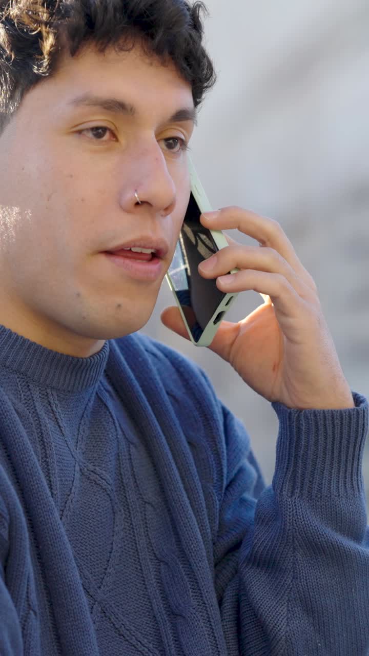Young latino man talking on mobile phone. Vertical