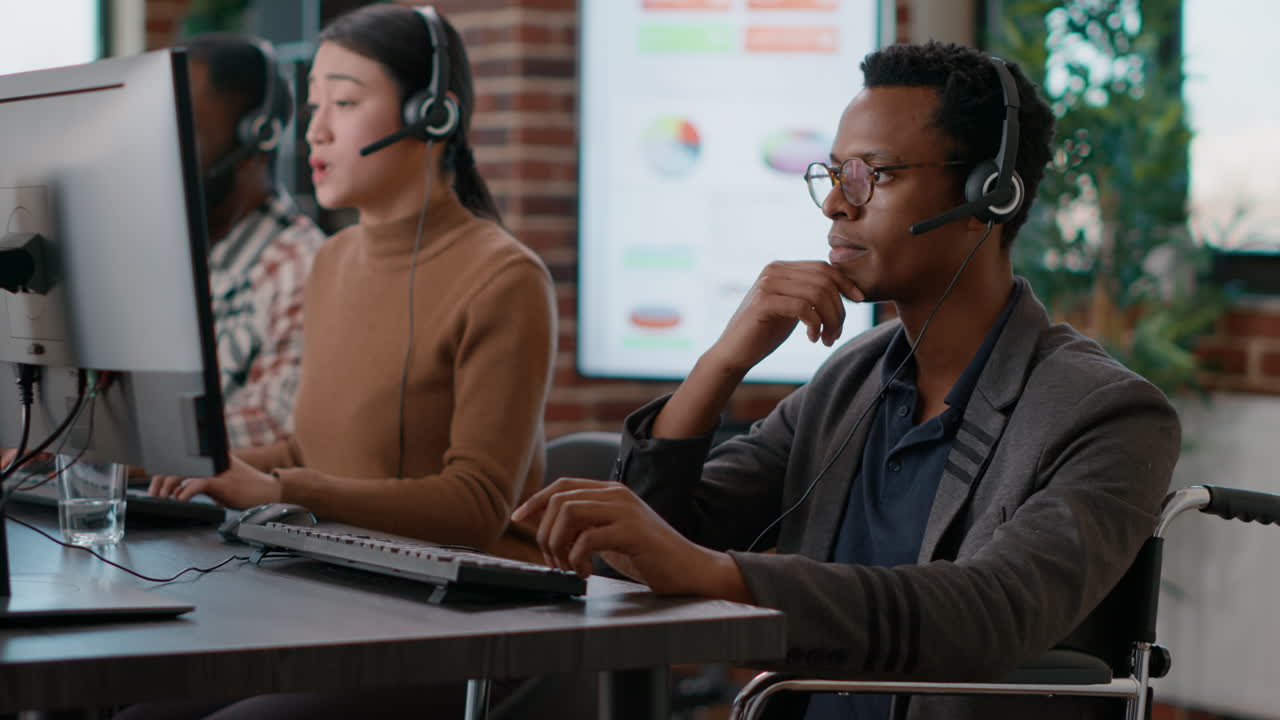 African american man in wheelchair answering call on headset