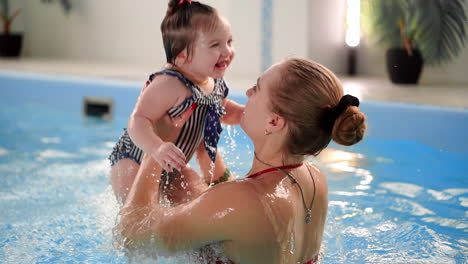 Happy smiling toddler is jumping and diving under the water in the swimming pool. An underwater shot. Slowmotion