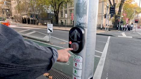 person pressing pedestrian button at traffic light