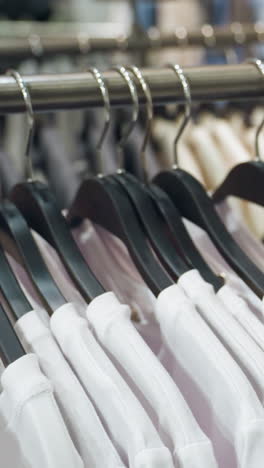 a clothing store displaying white and black shirts neatly arranged on hangers. this video highlights the organized display and variety of apparel in a modern retail environment