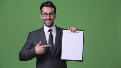 young handsome bearded persian businessman against green background