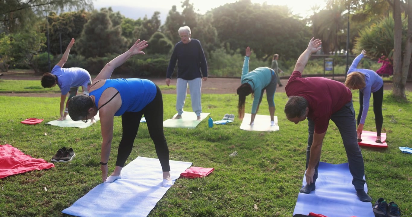 Anziani diversi che praticano yoga e stretching all'aperto