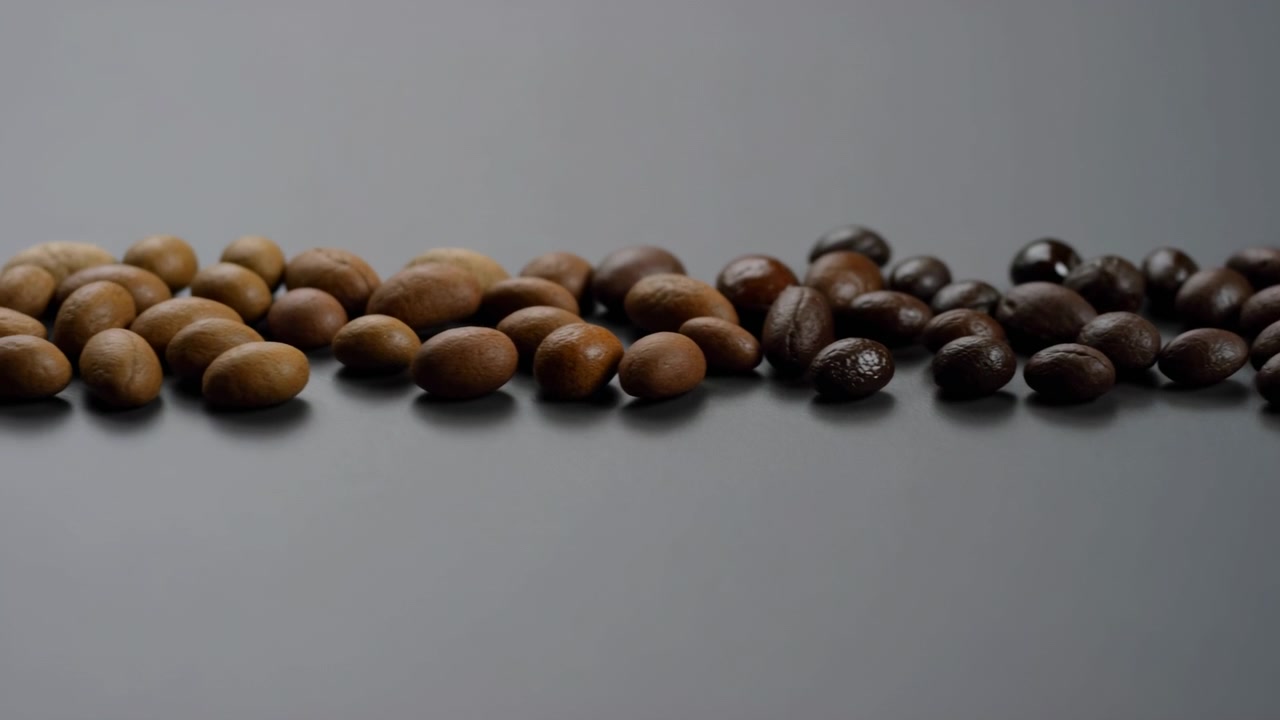 Coffee beans arranged in a line, in neutral gray background, with coffee beans, from a frontal view perspective, with brown, gray accents, and calm and organized mood, nearby objects.