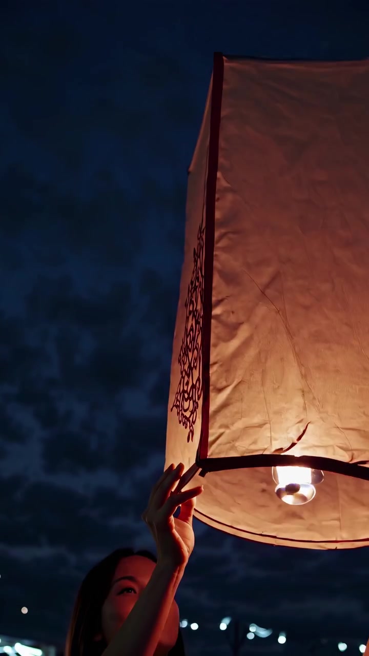 Giovane donna che tiene una lanterna volante luminosa di notte