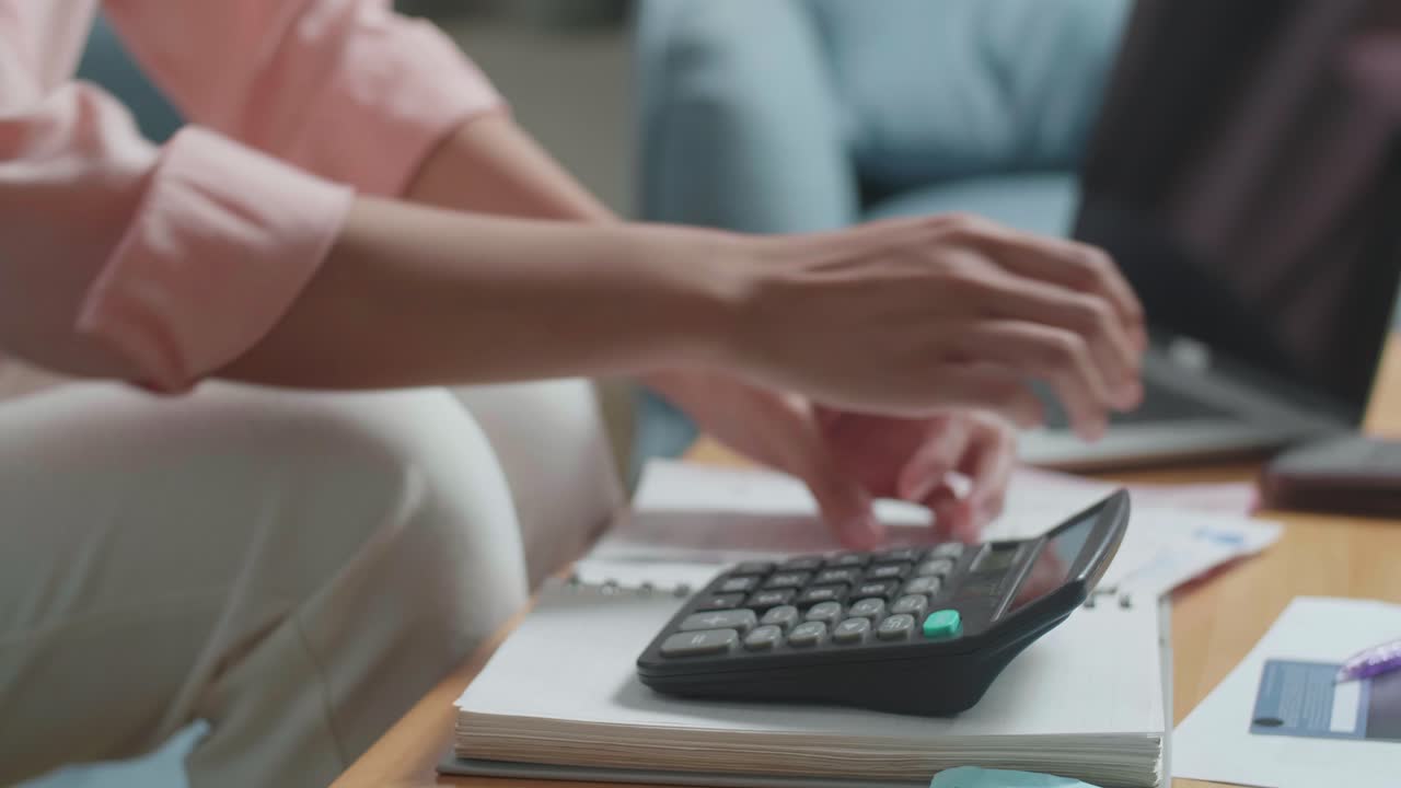 cerca de la mano de la mujer calculando dinero con una calculadora antes de abrir el bolso para comprobar el dinero