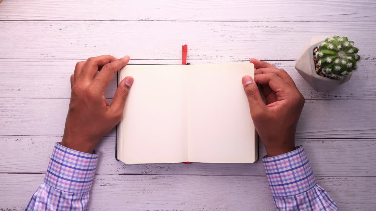 Person holding open notebook on wooden desk