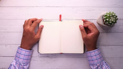 person holding open notebook on wooden desk