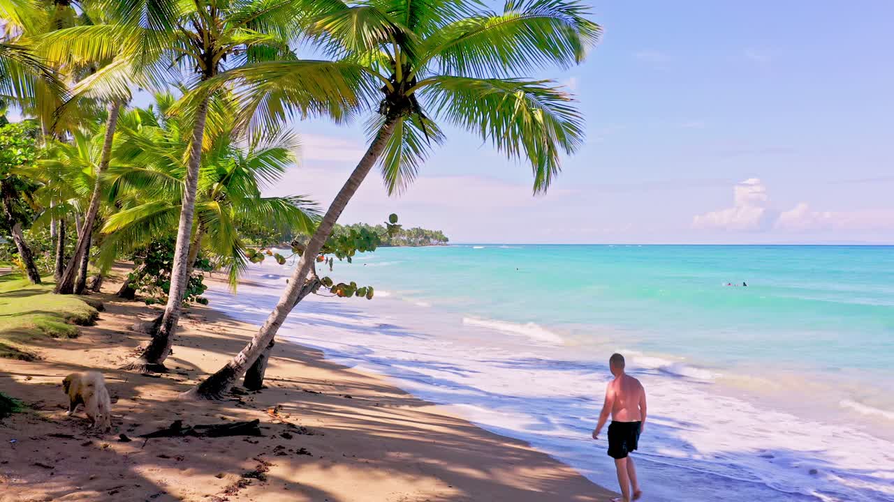 hombre caucásico caminando en una playa tranquila en playa bonita, república dominicana - tiro ancho