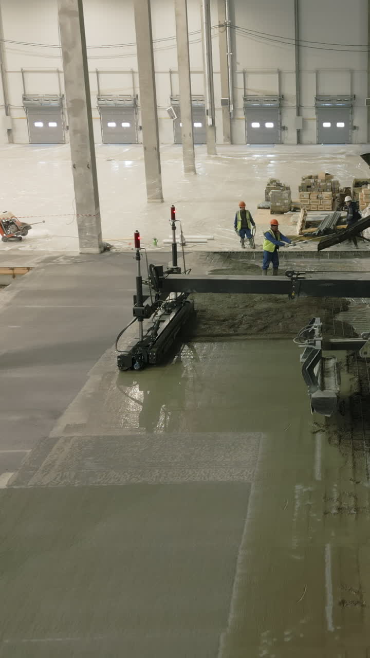 Concrete pouring and leveling in a warehouse construction site
