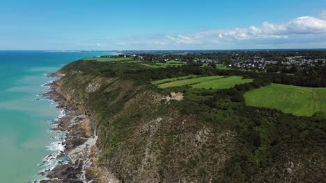 from above, the cabane vauban appears nestled atop the wild cliffs of carolles, surrounded by wind-swept grass and the vast sea below