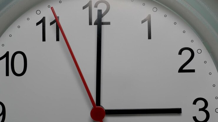 Close-up of a white clock face suggesting the passing of time. Round white clock with black Arabic numerals