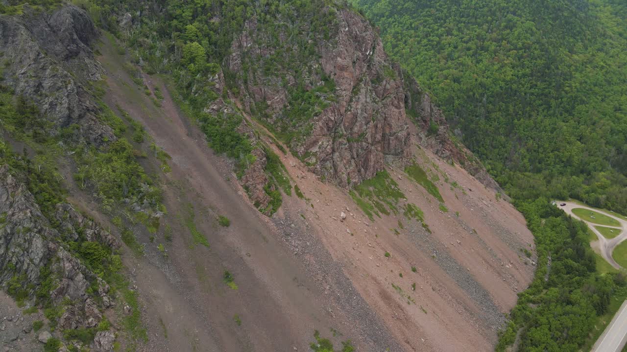 Drone shot going backwards revealing the surrounding beautiful vistas of the Cabot Trail mountains located on Cape Breton Island in Nova Scotia, Canada shot in 4k during the summer