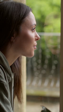 vertical video close up of woman at home in lounge looking out of window