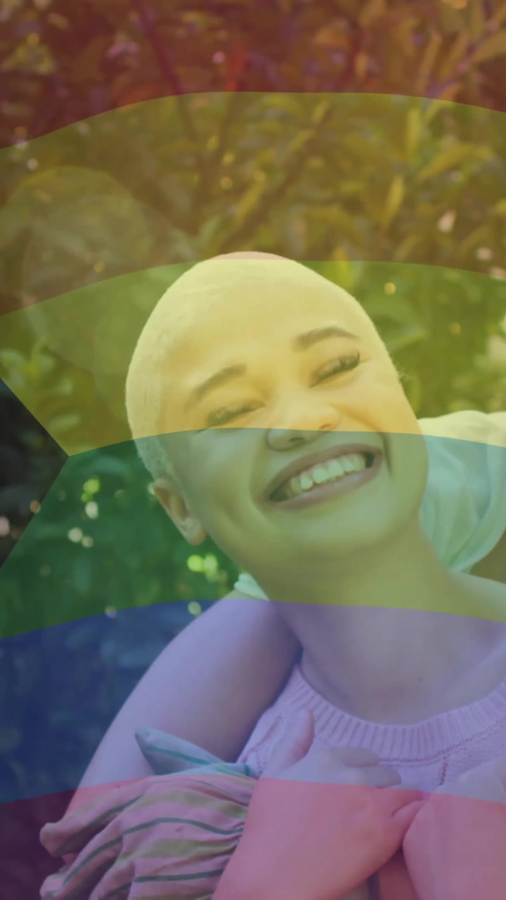 Animation of rainbow flag over diverse female couple embracing