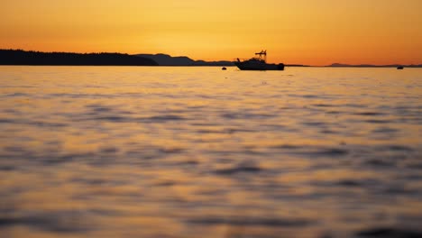 wide shot of small boat on calm ocean at sunset in slow motion